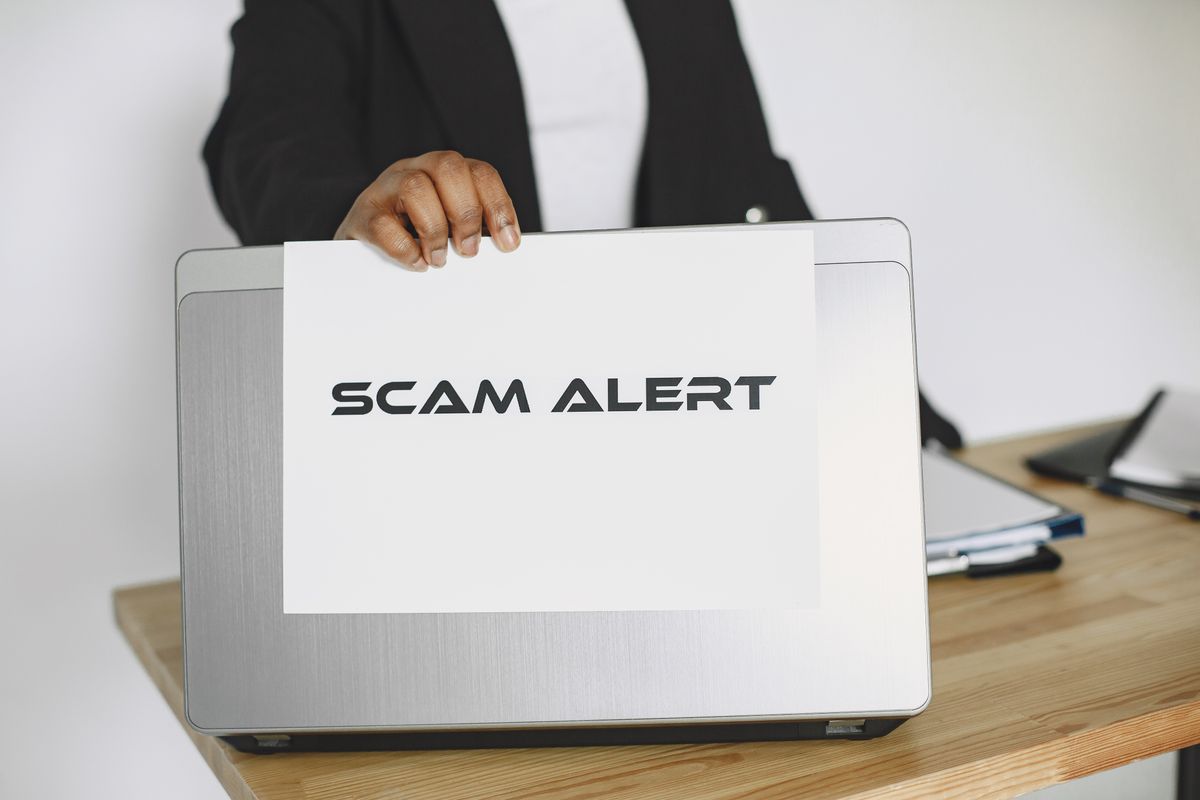 India job scam registration fee warning 2026 - person holding scam alert sign