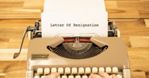 A person typing a letter of resignation on a typewriter