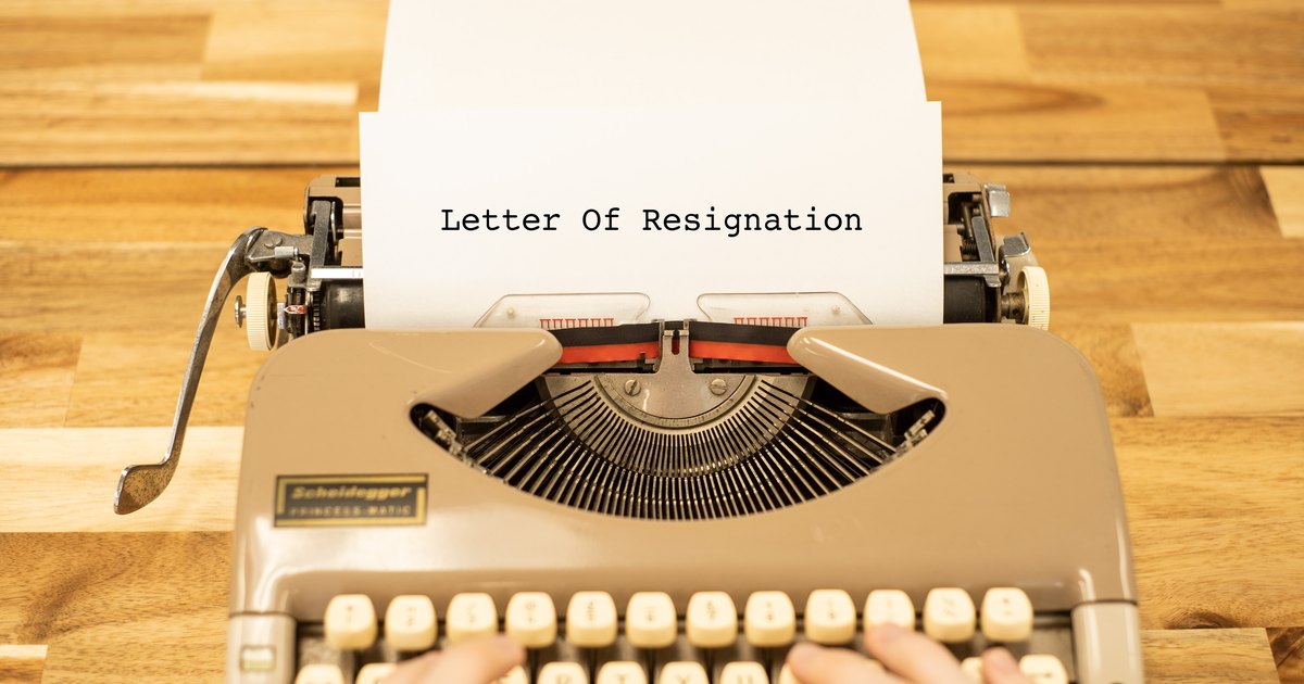A person typing a letter of resignation on a typewriter