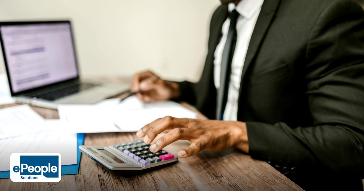 Employee Secondments India to Saudi Arabia: Legal Guide - a businessman in a black suit using a calculator at a desk