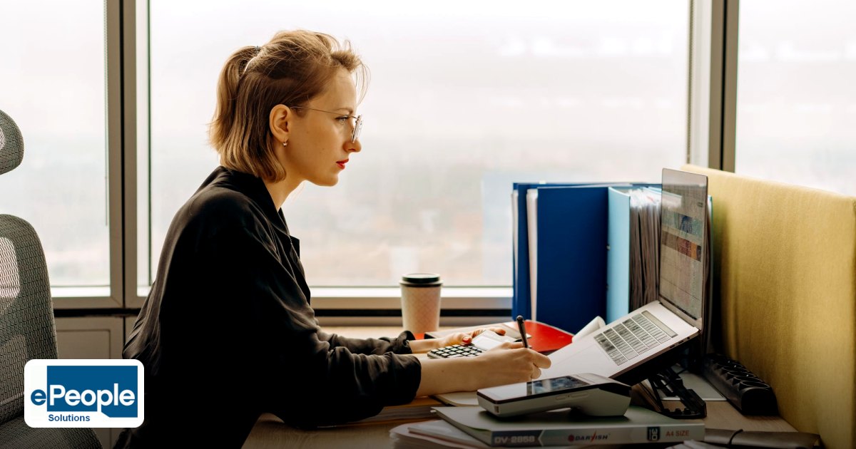 Payroll Outsourcing vs Third Party Payroll Staffing - dedicated woman using laptop and calculator in modern office setting