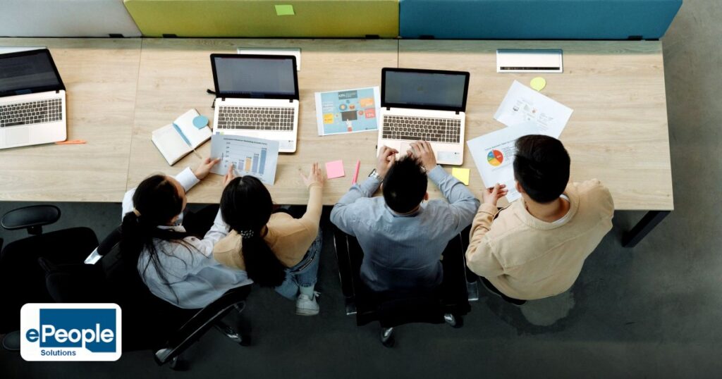 Corporate Training UAE Indian Talent 2026: Top Programs - aerial view of four colleagues working with laptops and documents
